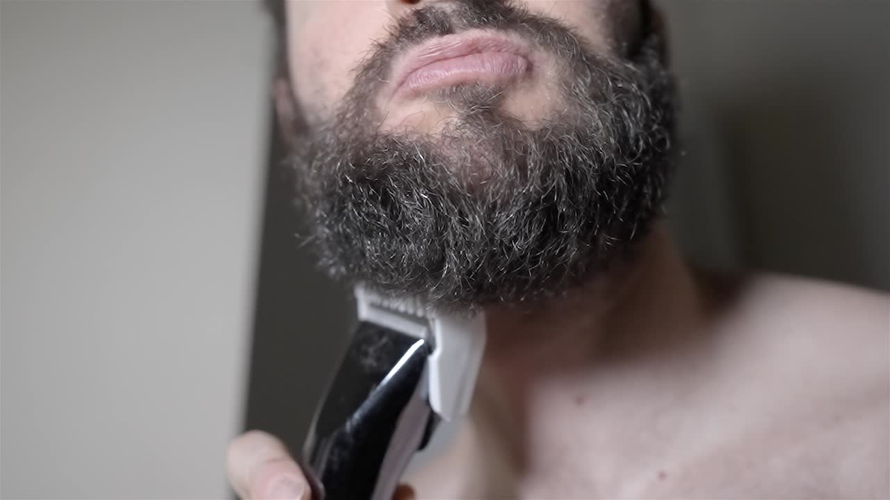 Man Starts Shaving Thick Beard Electric Razor Closeup