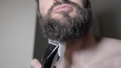 man starts shaving thick beard electric razor closeup