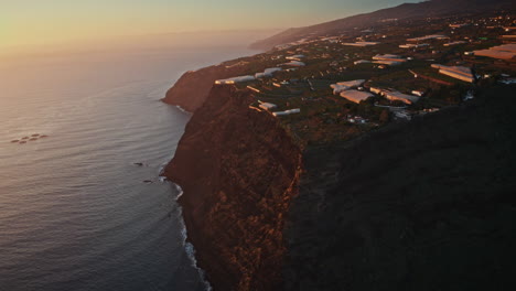 drone aéreo disparado sobre la costa alta al atardecer en la isla de la palma, islas canarias, españa. vista de los escarpados acantilados volcánicos y las vastas olas del océano aplastando las rocas.