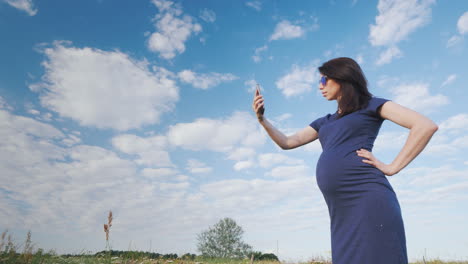 Mujer-Embarazada-Tomando-Una-Foto-Contra-El-Cielo-Azul
