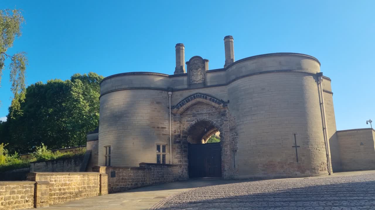 Revealing shot of the gate of Nottingham Castle under a bright blue evening sky, highlighting the historic landmark and popular sightseeing attraction in Nottingham, UK