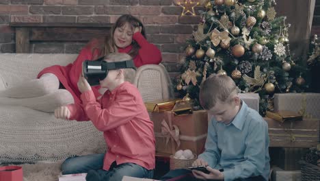 cute-blond-mother-relaxes-on-sofa-sons-play-with-gadgets