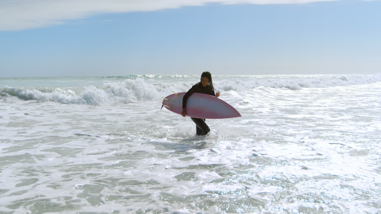mujer con tabla de surf corriendo en el mar 4k