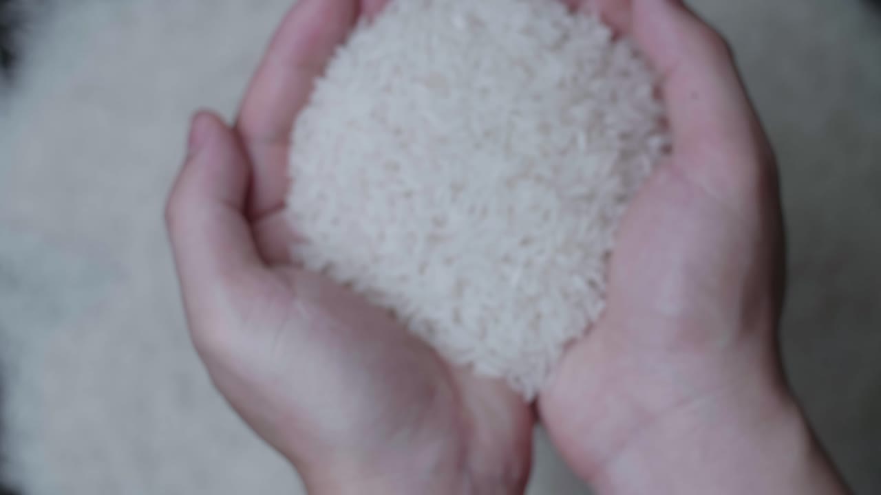 Someone Hand Raw Rice And Show Up In Slow Motion, Over White Rice Grains Background