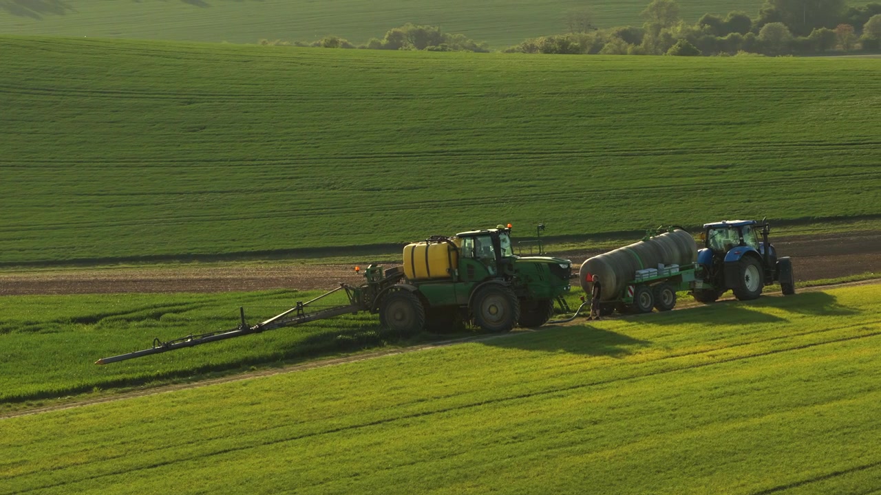 Vista aerea con drone di un piccolo villaggio ceco con case dai tetti rossi immerso tra dolci colline verdi e campi arati con un filare di alberi frangivento, Moravia, Repubblica Ceca