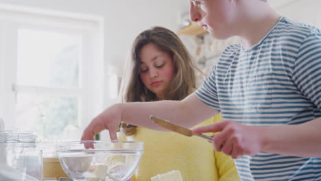 Junges-Down-Syndrom-Paar-Fügt-Butter-Zum-Kuchenrezept-Hinzu,-Das-Sie-Zu-Hause-In-Der-Küche-Backen