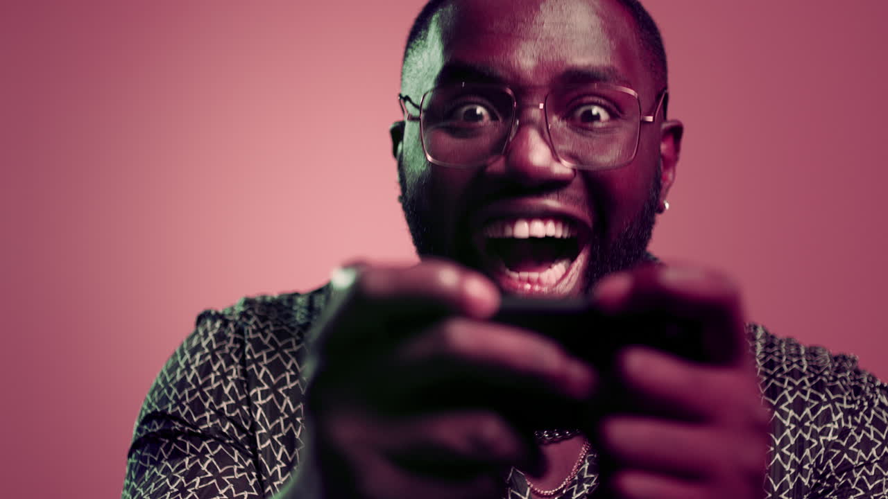 성공한 남자가 스튜디오에서 승리합니다. 성공한 아프리카 남자가 실내에서 스마트폰을 사용합니다.