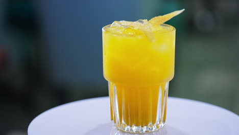 orange tasty cocktail decorated with ice cubes and chips. beautiful beverage on the spinning table close up.
