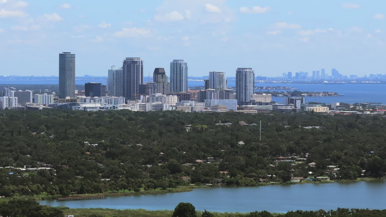 Aerial view of Downtown St Petersburg Florida. Buildings meet lush suburbs and bayfront views across Tampa Bay to Downtown Tampa skyline, showing urban growth and coastal living in a scenic cityscape