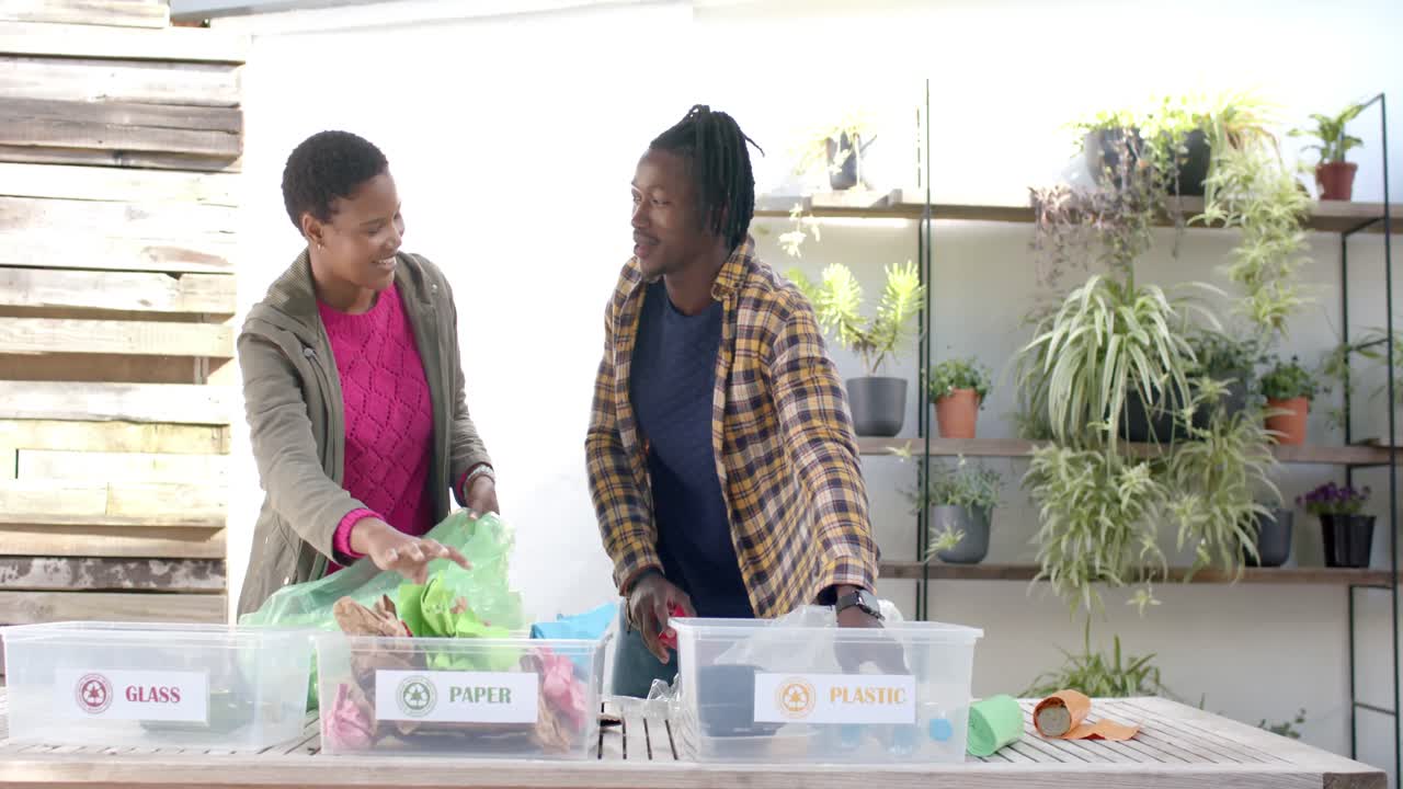 Happy african american couple collecting recycling at home, slow motion