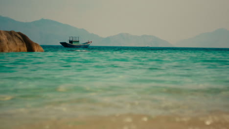 tranquil beach scene with fishing boat and mountains