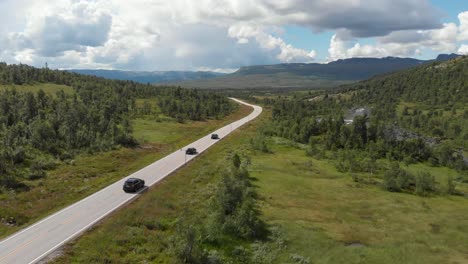 vehicles driving through mountain road on a sunny day in summer in norway