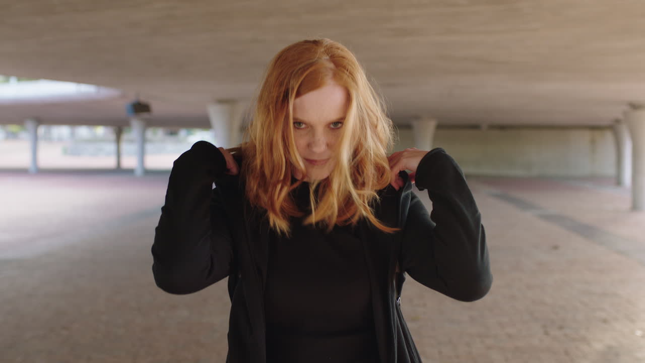 아름다운 젊은 여성 학생의 초상화 캠퍼스에서 호의적으로 미소 짓고 후디를 입고 있습니다.