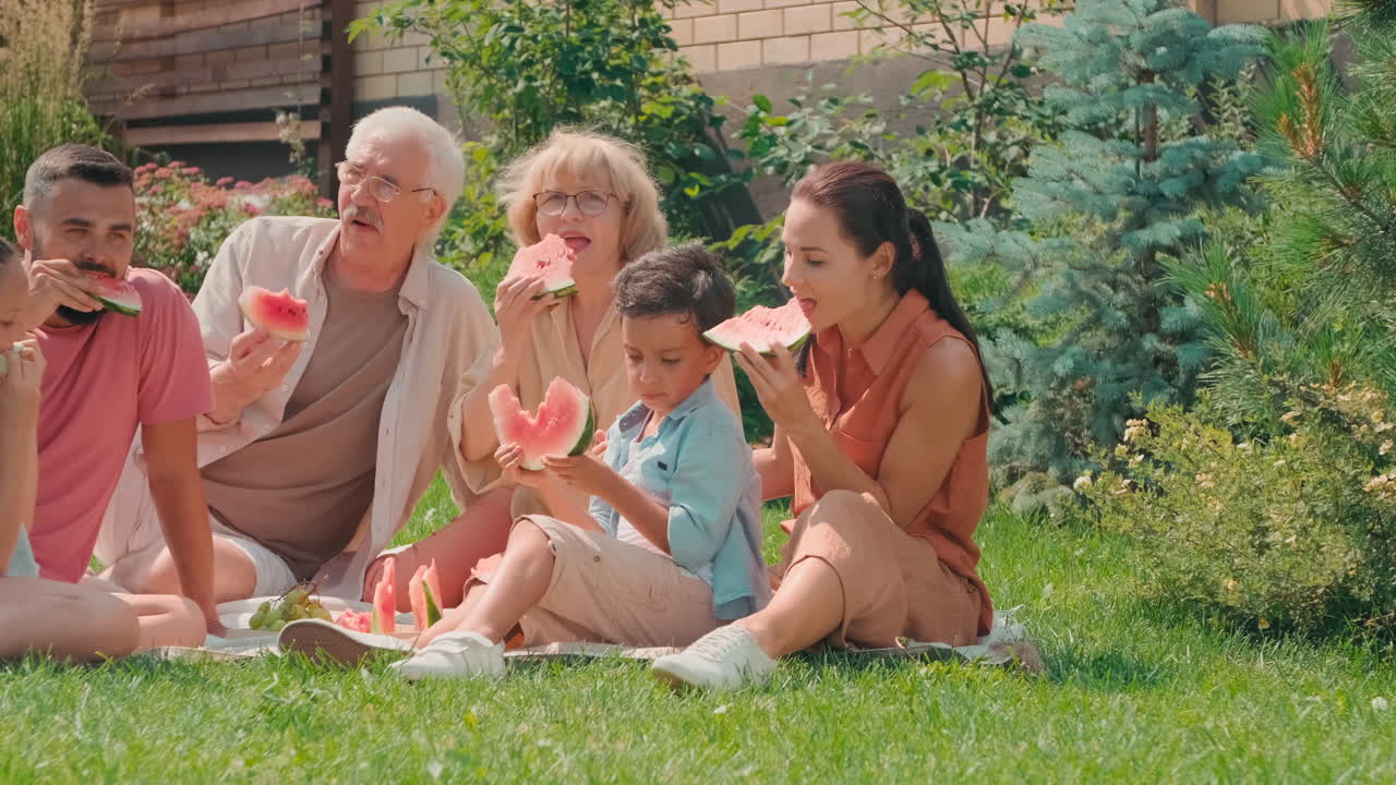 Big Family Eating Watermelon In Backyard