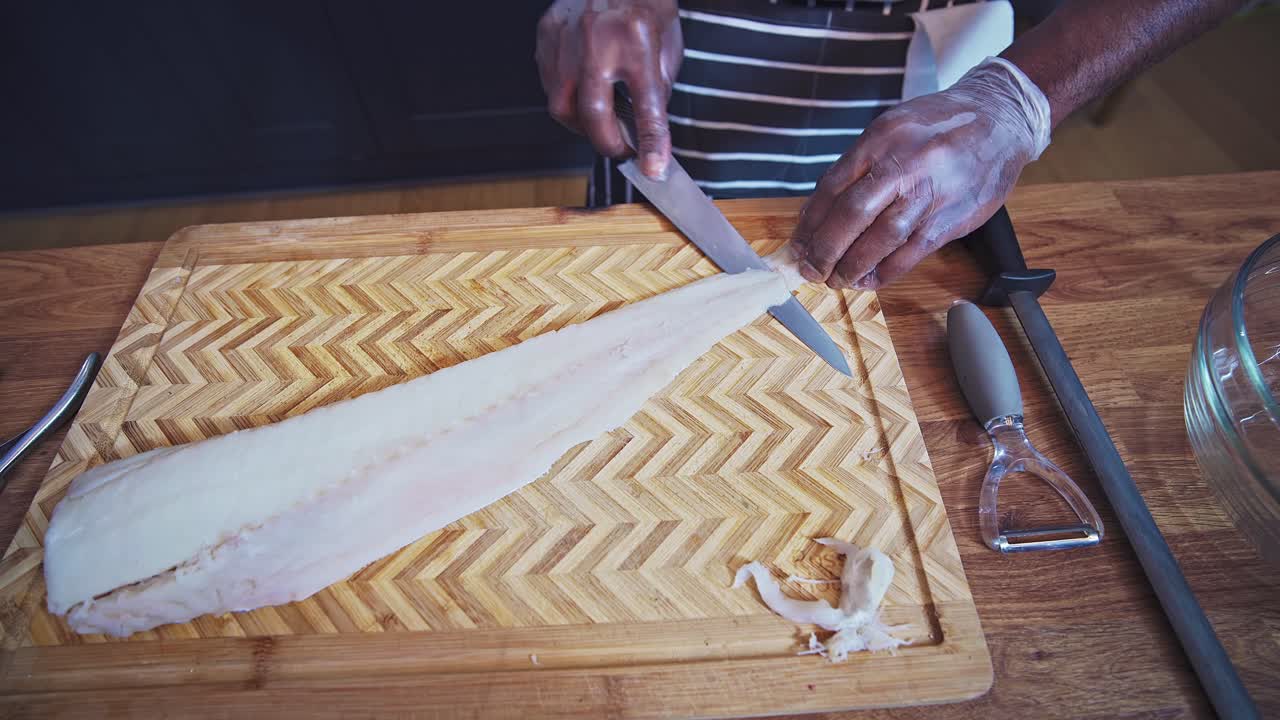 chef caribeño preparando pescado de bacalao en una tabla de cortar