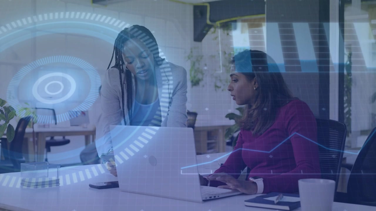 Mujer sentada escribiendo, colega que llega señalando, gráficos HUD resaltando datos de la computadora portátil para negocios.
