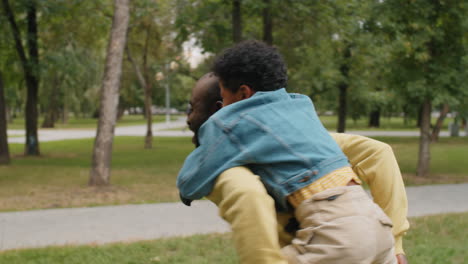 hombre afroamericano dando paseo a un hijo pequeño en el parque