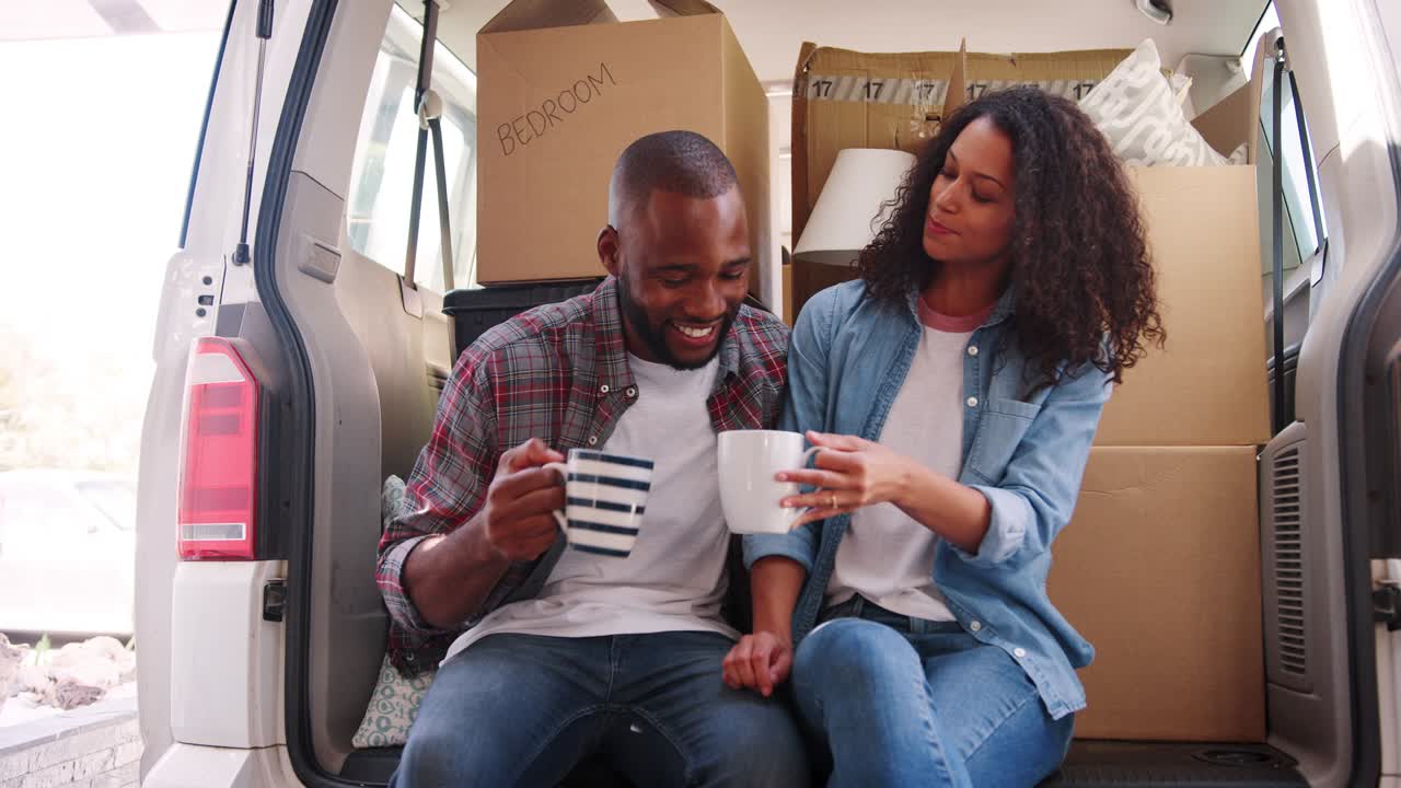 Slow Motion Shot Of Couple Taking A Break In Back Of Removal Truck On Moving Day