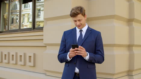 successful businessman using mobile phone outdoors. professional chatting online