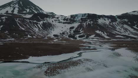 rivers in dark, frozen tundra landscape of iceland mountains in the winter - aerial