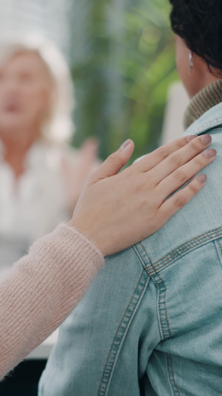 Una mano palmea suavemente el hombro, ofreciendo consuelo y apoyo