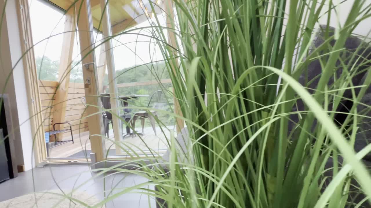 View from a small wooden chalet house in the mountains outside through a glass door and window. Glamping and idyllic holidays. View from the glamping tent on the table and chairs on the terrace