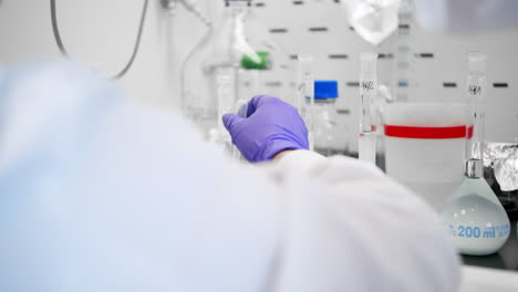 the lab scientist pours liquid into containers as part of the cure-seeking process