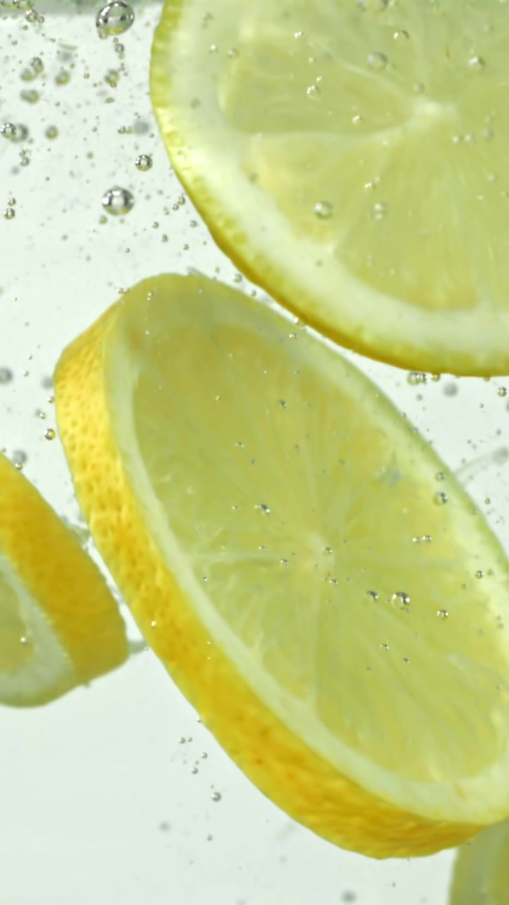 Fette di limone fresche galleggianti in acqua frizzante con bollicine