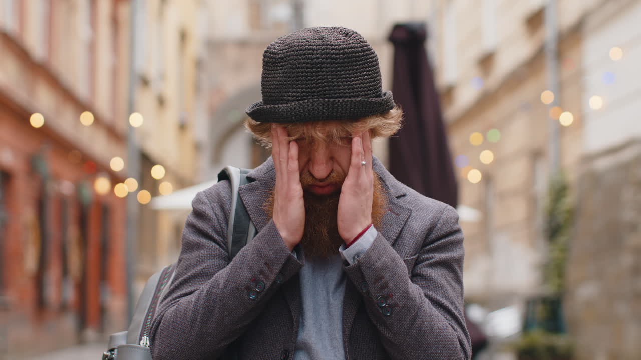 Sad unhappy frustrated young man walking alone in city street feeling bad annoyed grief problem