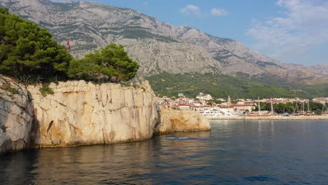 Male-cliff-jumper-doing-double-backflip-off-Croatian-clifftop,-aerial-view