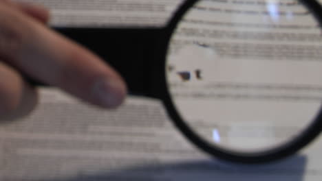 a magnifying glass passes over a paper revealing the words the fine print