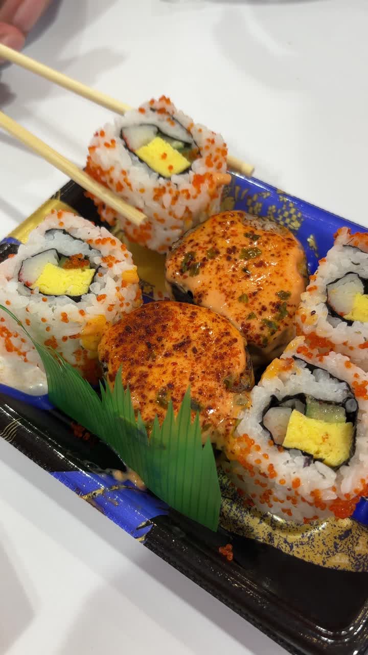 Sumpit Mengambil Gulungan Sushi dari Piring Saji Makanan Jepang