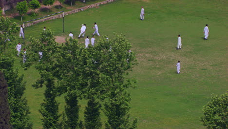 peshawar, pakistan, students playing foot ball aerial view from the trees, students are in white shalwar kameez uniforms