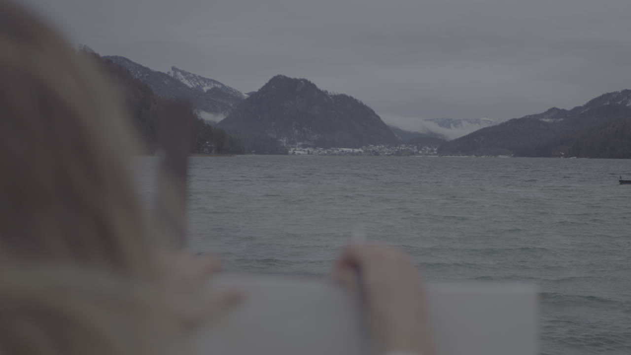 Artist sketching by a lake in winter scenery