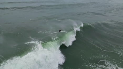 Toma-Aérea-De-Un-Surfista-Saliendo-A-Atrapar-Una-Ola-Grande