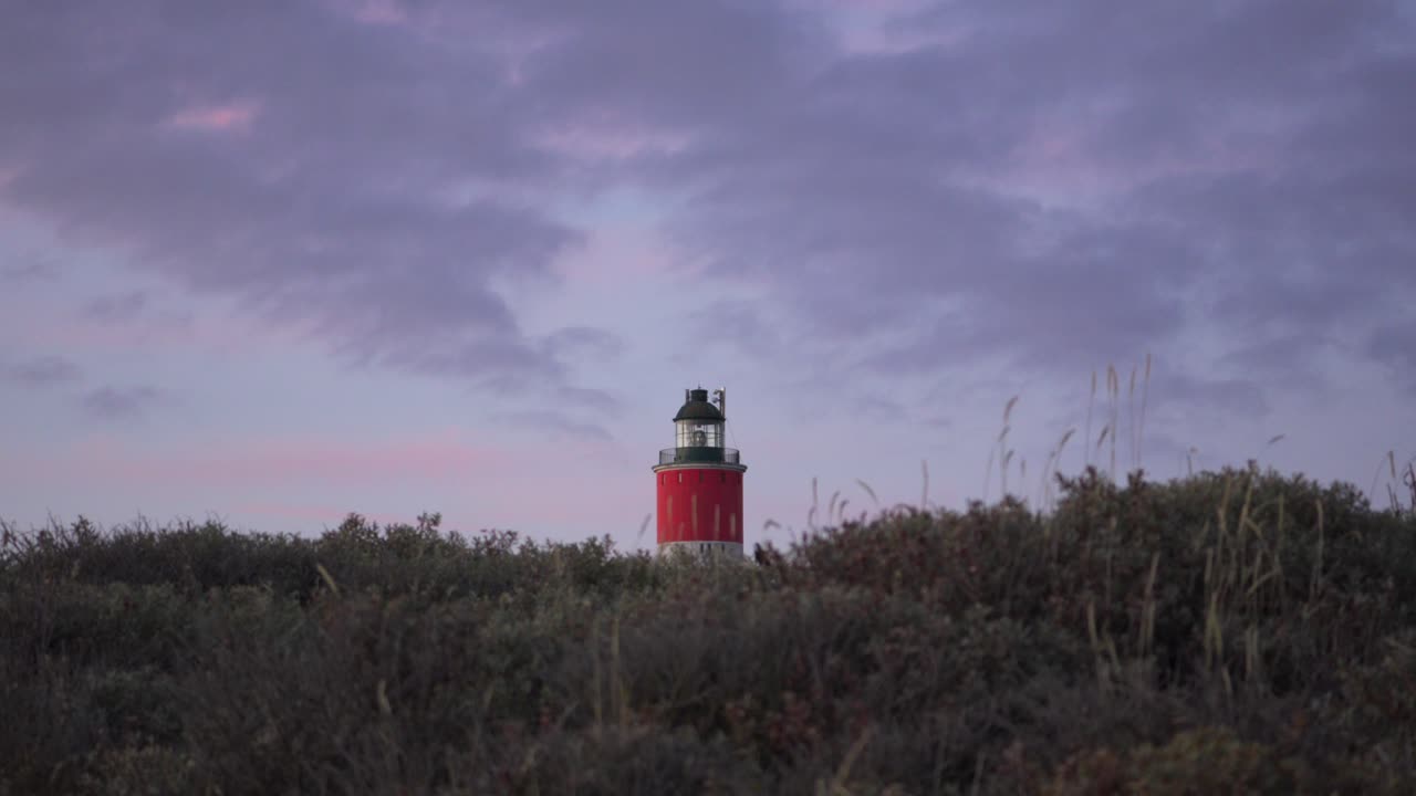 Il faro si erge sopra le dune costiere sulla Costa d'Opale sotto un cielo dai colori pastello.