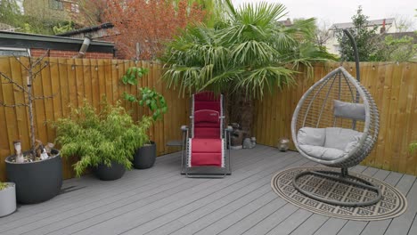 Minimalistic-UK-summer-garden-showing-swing-chair-decking-and-sun-lounger