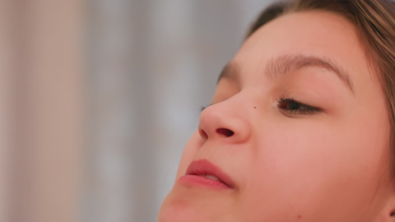Extreme close up of young woman in motion during lighthearted pillow fight moment, arm raised and hair blurred with movement as pillow connects