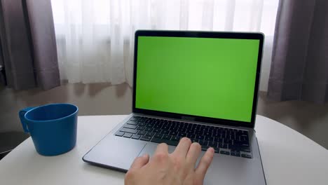 hombre con la mano usando el trackpad (touchpad) para usar la computadora portátil con pantalla verde