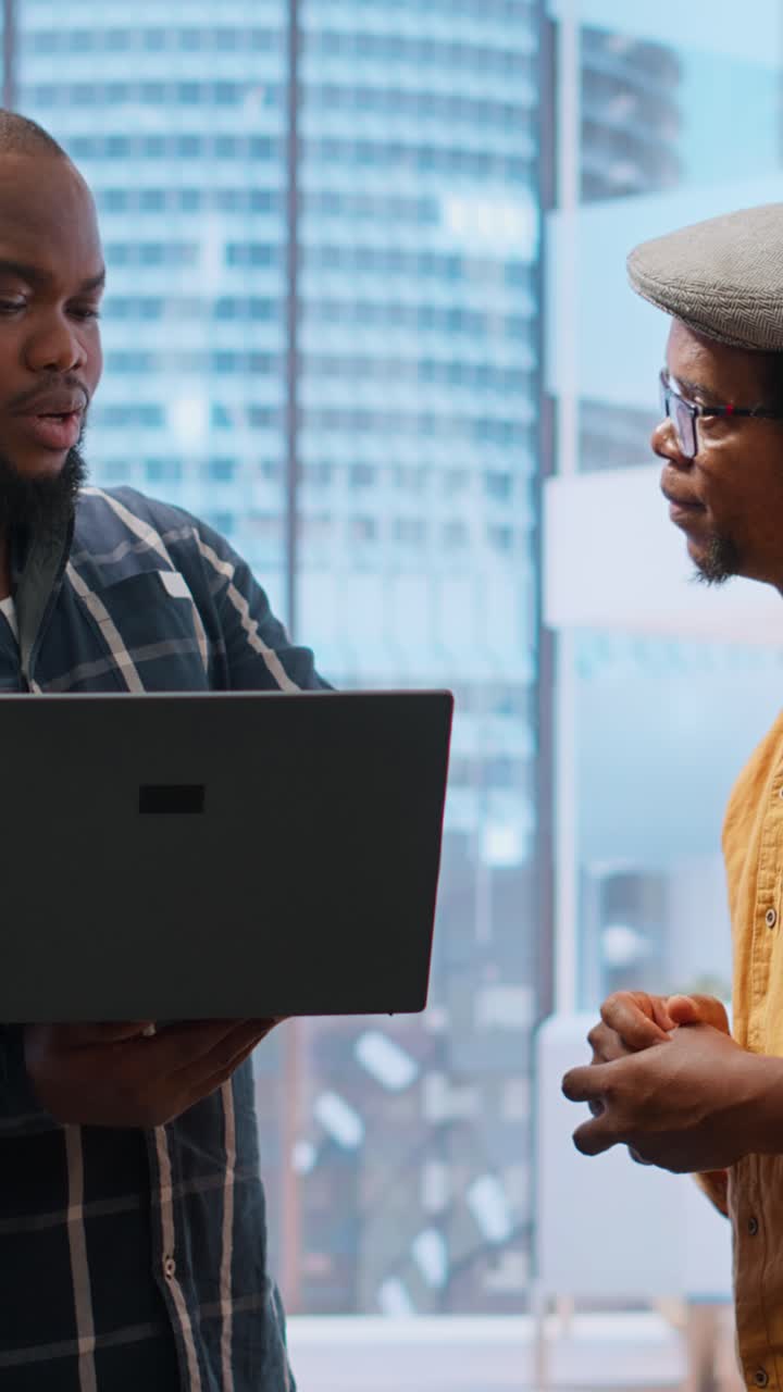 Two Men Discussing Business Project on Laptop in Modern Office