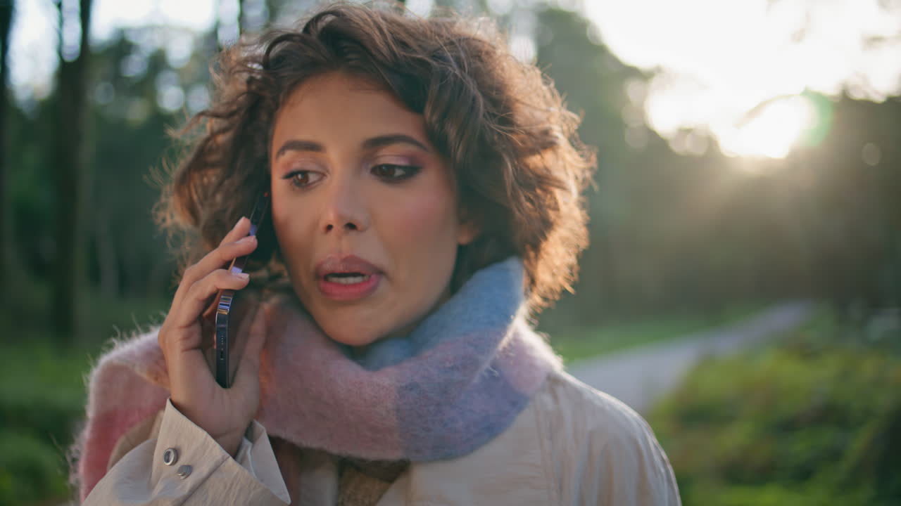 Serious woman ending call on phone at sunlit forest closeup. Lady talking nature