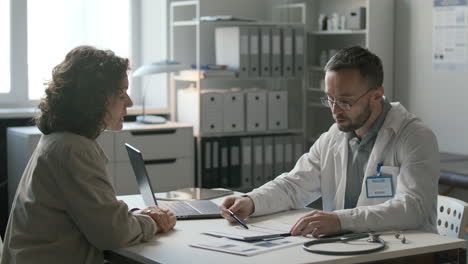 doctor discussing medical records with female patient in clinic