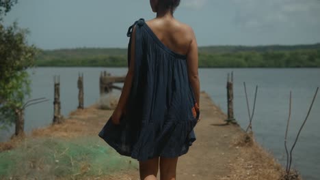 In-a-serene-natural-environment,-a-beautiful-Indian-woman-gracefully-walks-along-the-seawall,-radiating-elegance-and-tranquility