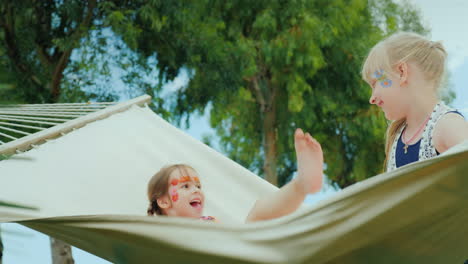 Two-Children-With-Painted-Faces-Play-Fun-On-A-Hammock-Laugh-And-Enjoy-The-Holidays