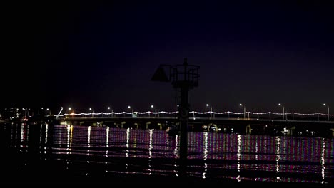 puente iluminado que se refleja en el río por la noche