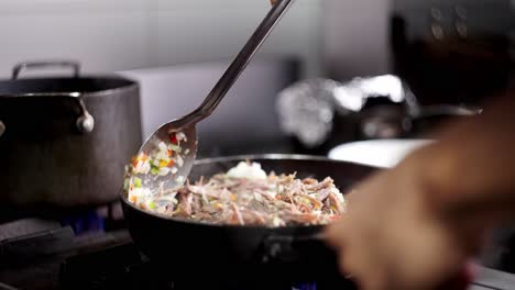 close up view of a metal spoon stirring beef stew with vegetables in a pan in slow motion.