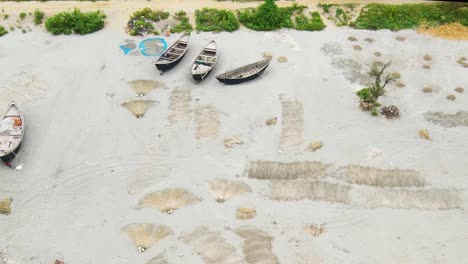 aerial-showing-traditional-wooden-fishing-boat,-fishing-net-repair,-fishermen,-Kuakata-Sea-Beach-shore,-Bangladesh,-fishing-village