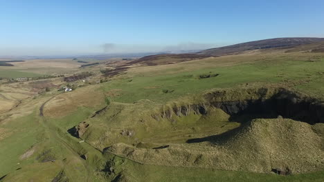 aerial view of a disused quarry, moving towards the quarry on a bright sunny day