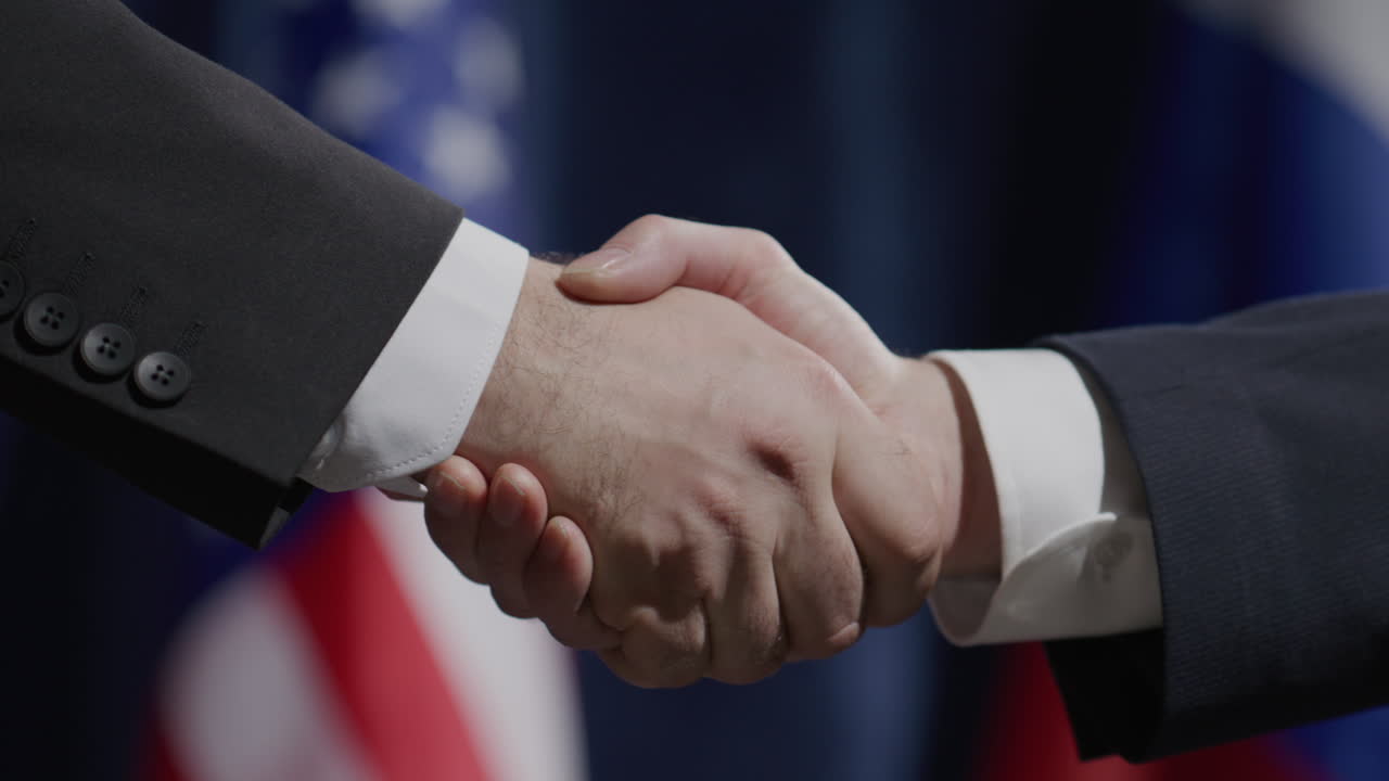 Close-Up of Politicians Shaking Hands in front of National Flags