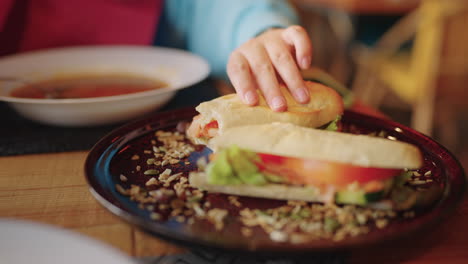 persona comiendo un sándwich y sopa